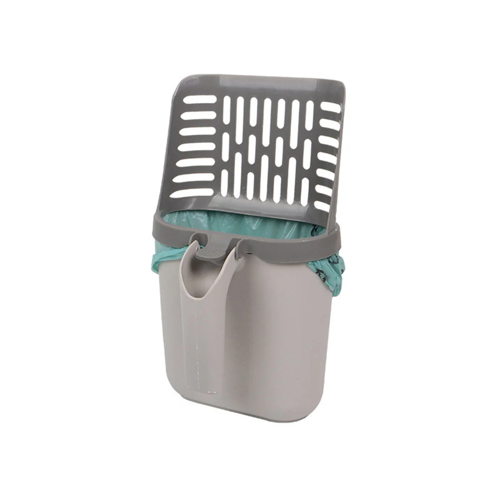 A grey cat litter scoop resting on a waste bin with a blue liner.