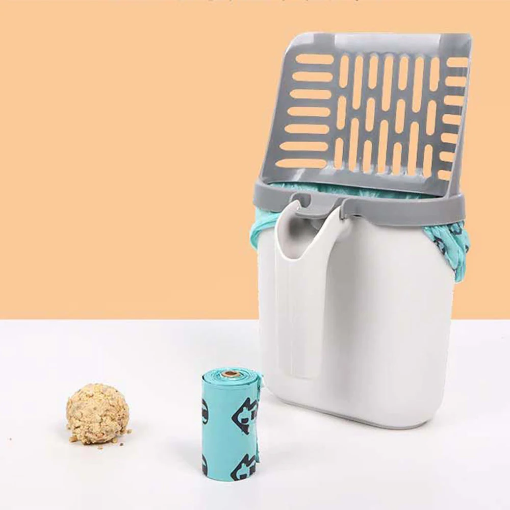 A white and grey cat litter scoop holder with a teal liner, shown with a roll of bags and a clump of litter.