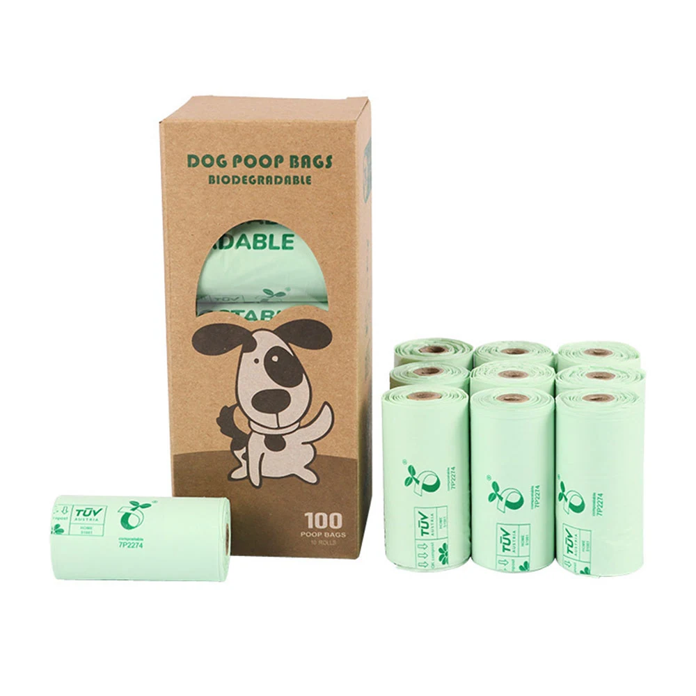Kraft paper box labeled Dog Poop Bags Biodegradable with a cartoon dog, surrounded by rolls of light green bags.