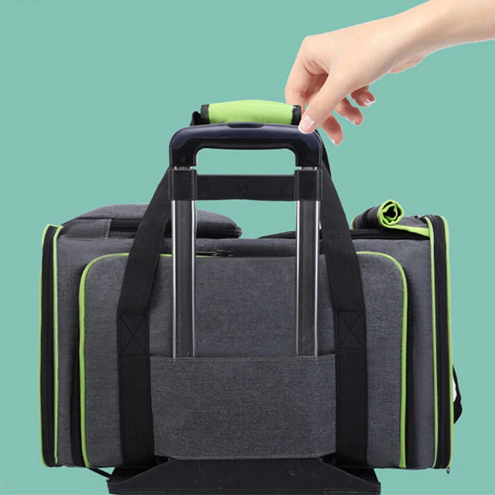 A hand grips the green handle of a rolling suitcase, which is attached to the back of a gray duffel bag.
