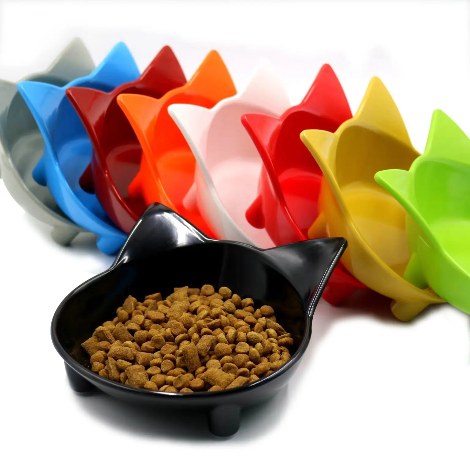 A row of colorful cat-head shaped bowls with a black one in the foreground filled with dry pet food.