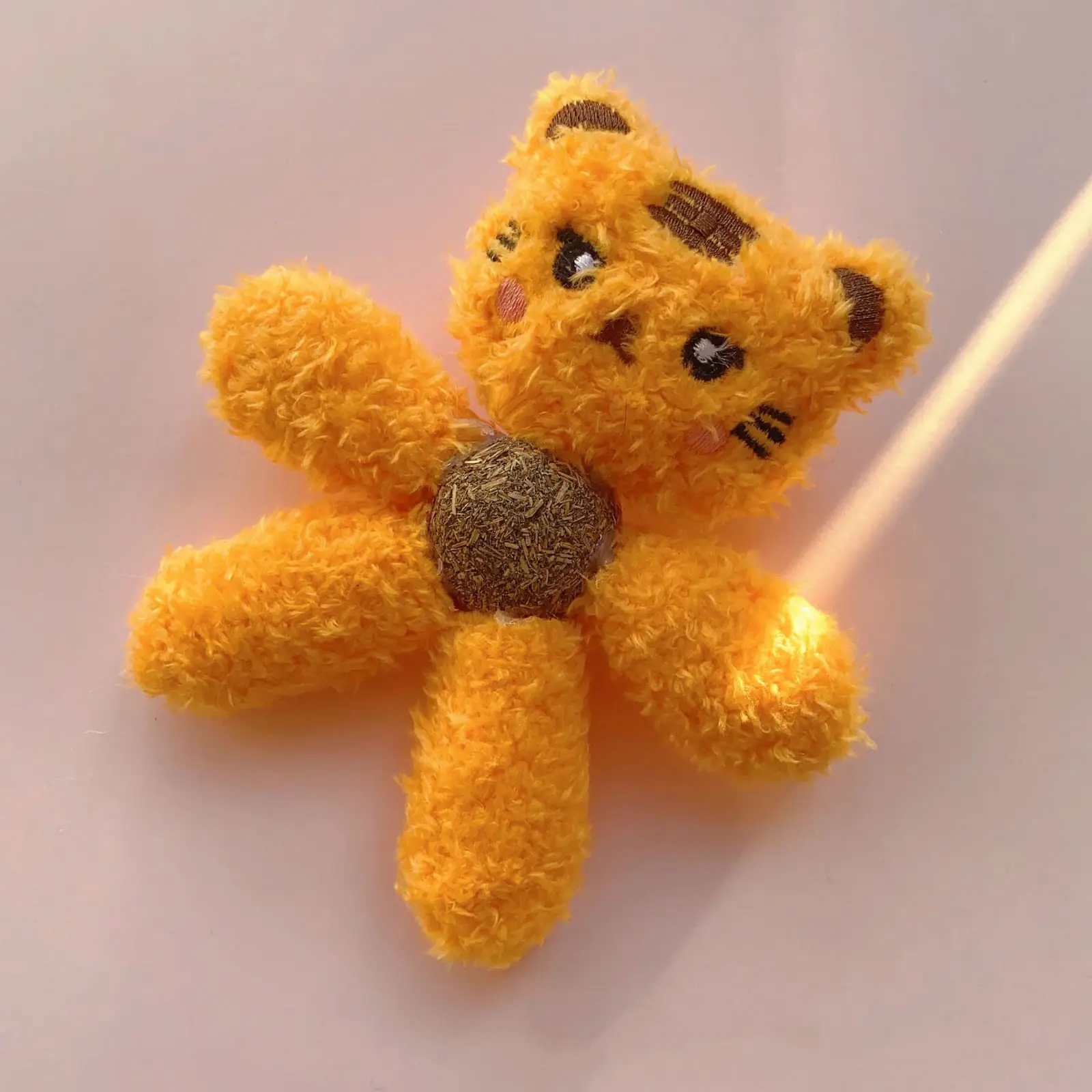A fuzzy orange plush flower with a tiger face and a brown center on a white background.