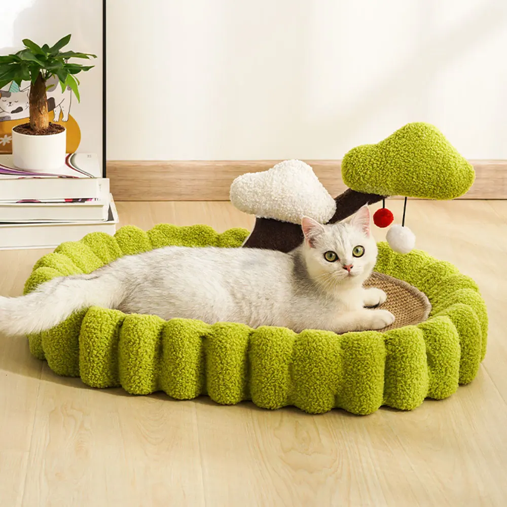 A white cat relaxing in a green, fluffy, tree-shaped pet bed on a wooden floor.