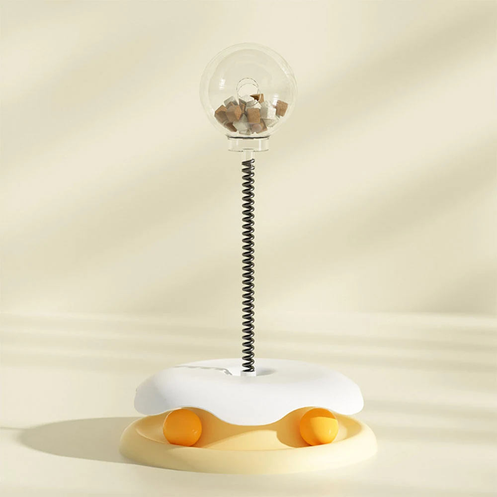 Vertical product shot of a cat toy featuring a clear ball on a spring attached to a white base with orange elements.