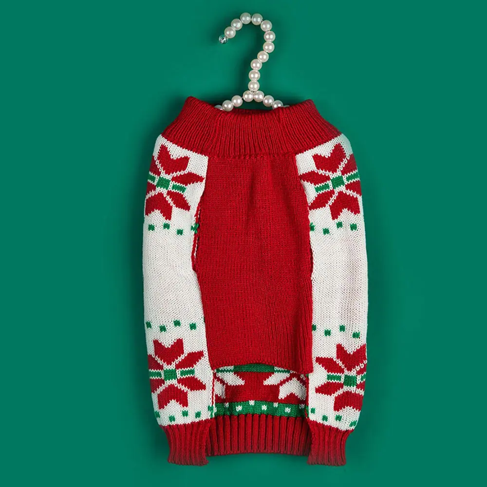 Red and white knitted sweater featuring snowflake patterns hanging on a pearl hanger against a green background.