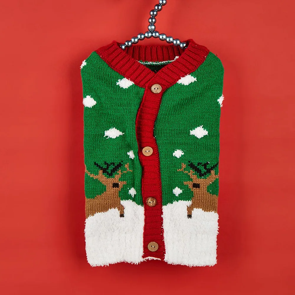 Green and red knitted sweater with a reindeer pattern hanging on a silver beaded hanger.