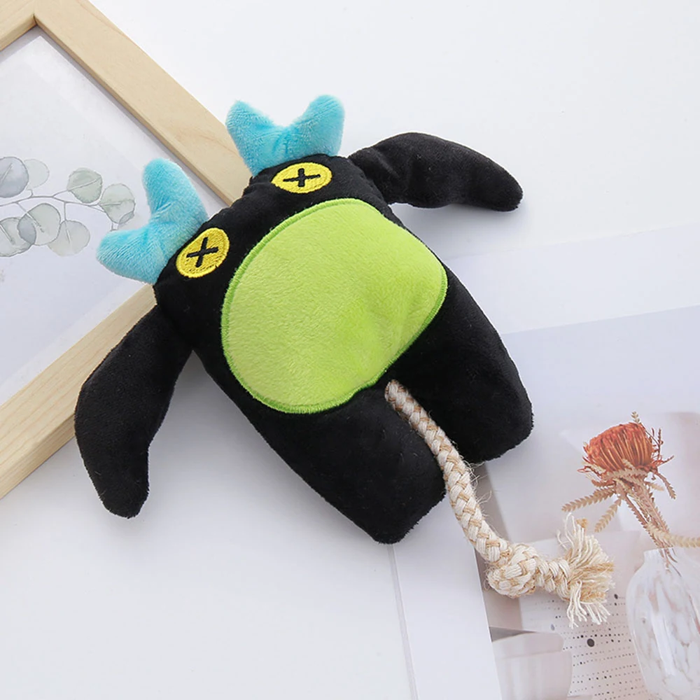 Black plush toy with green belly and blue horns lying on a white surface