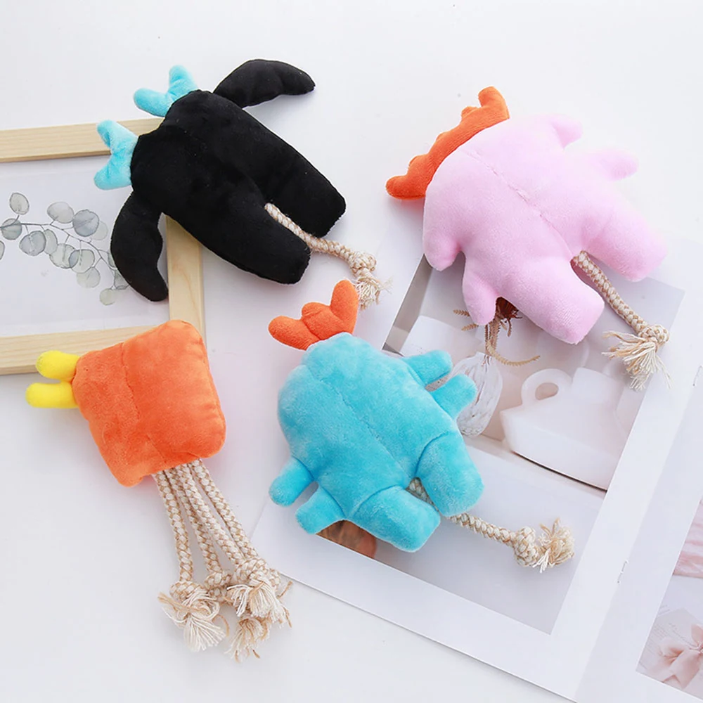 Four plush dinosaur toys with rope tails arranged on a white surface near a framed picture and magazine