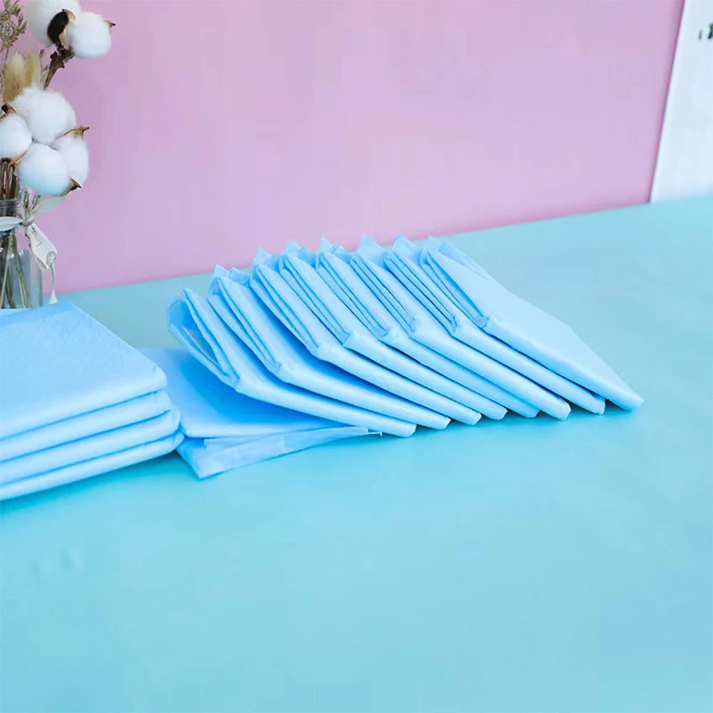 Stacks of light blue folded fabric pads on a blue table with cotton stems in the background.