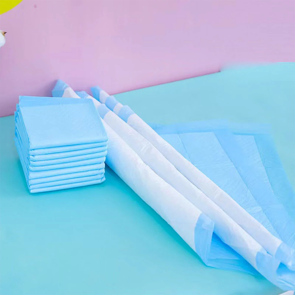 A stack of folded blue disposable underpads and two rolled pads on a blue surface.