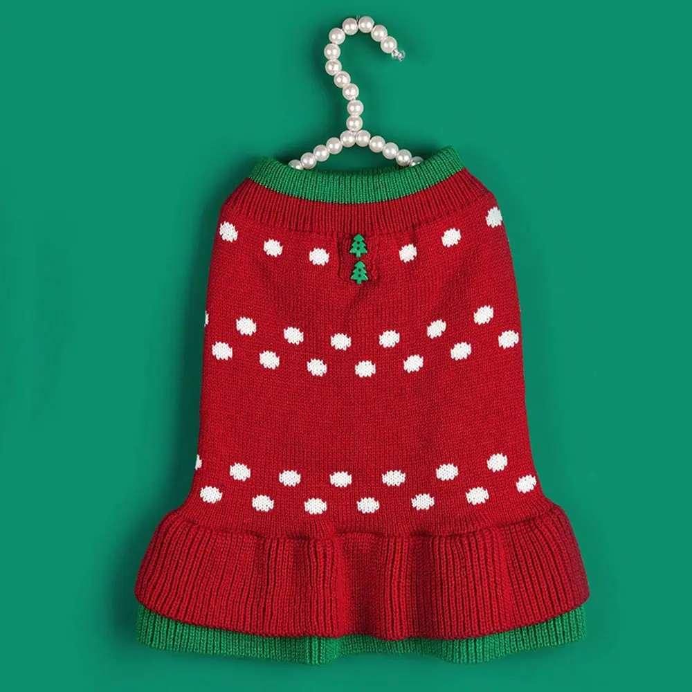 Red knitted pet sweater with white dots and green trim hanging on a pearl hanger.