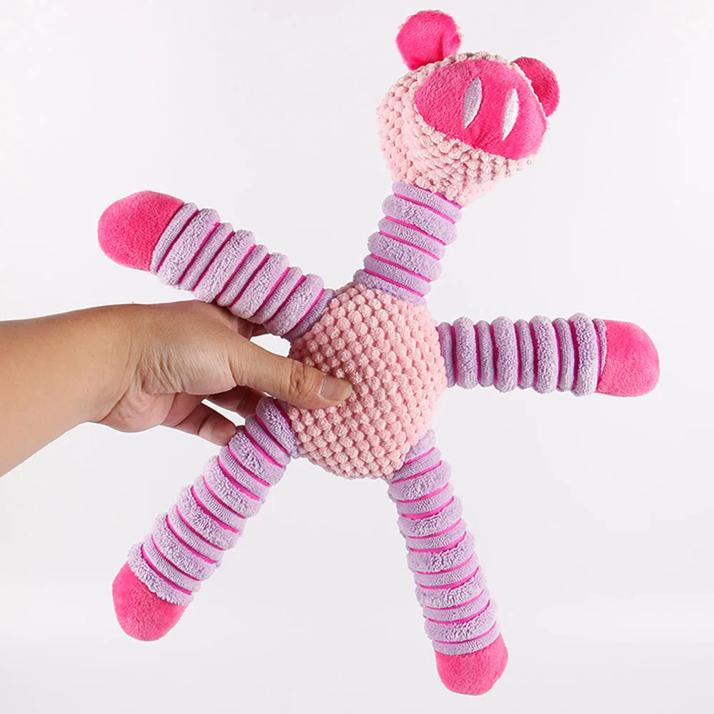 A hand holding a pink and purple star-shaped plush dog toy with a textured center and striped limbs.