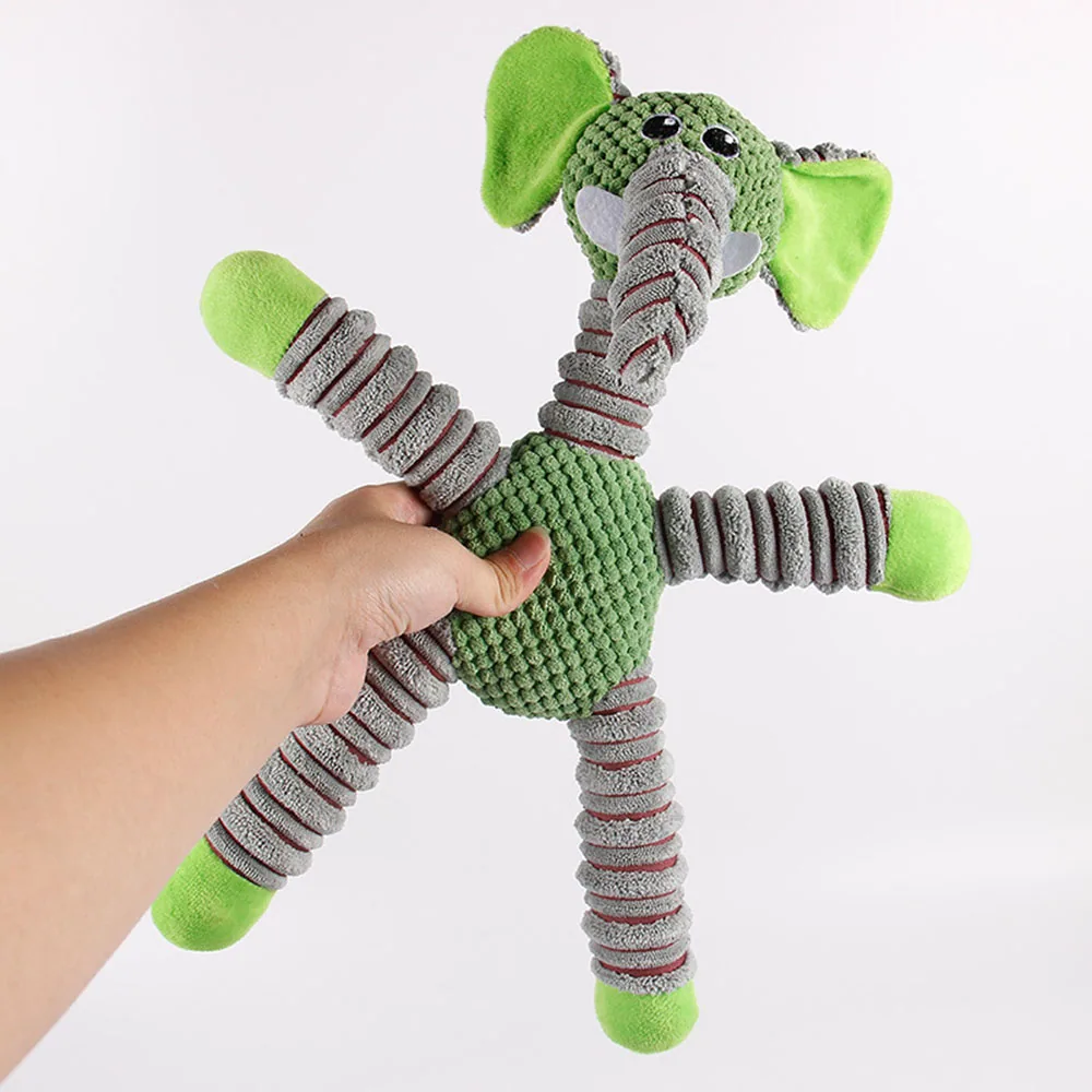 Hand holding a green and gray plush elephant toy with striped limbs against a white background