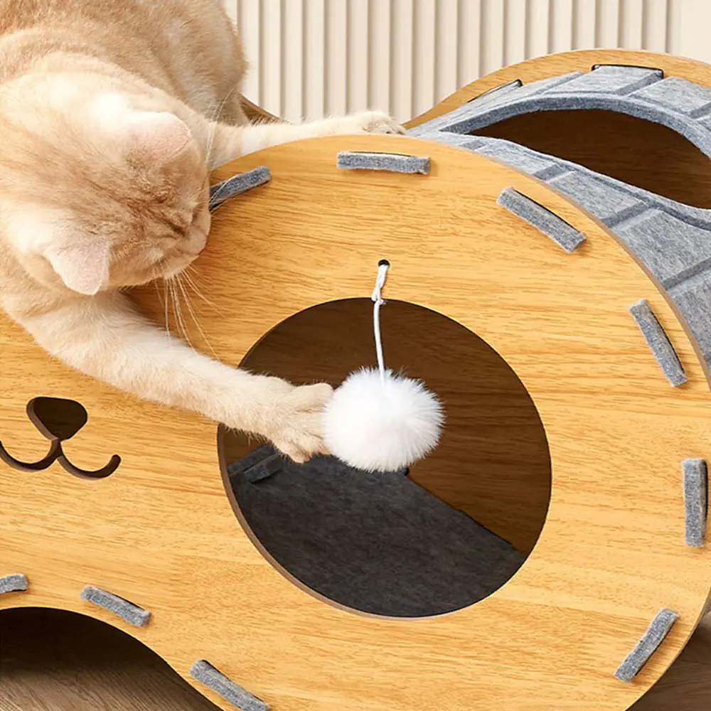 Orange cat playing with a hanging ball toy on a wooden cat house.