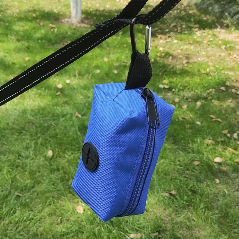 Blue fabric storage pouch hanging from a black strap against a grassy background