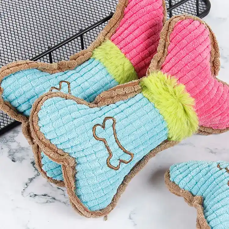 Multiple blue and pink bone-shaped plush dog toys with faux fur trim and embroidered bones.