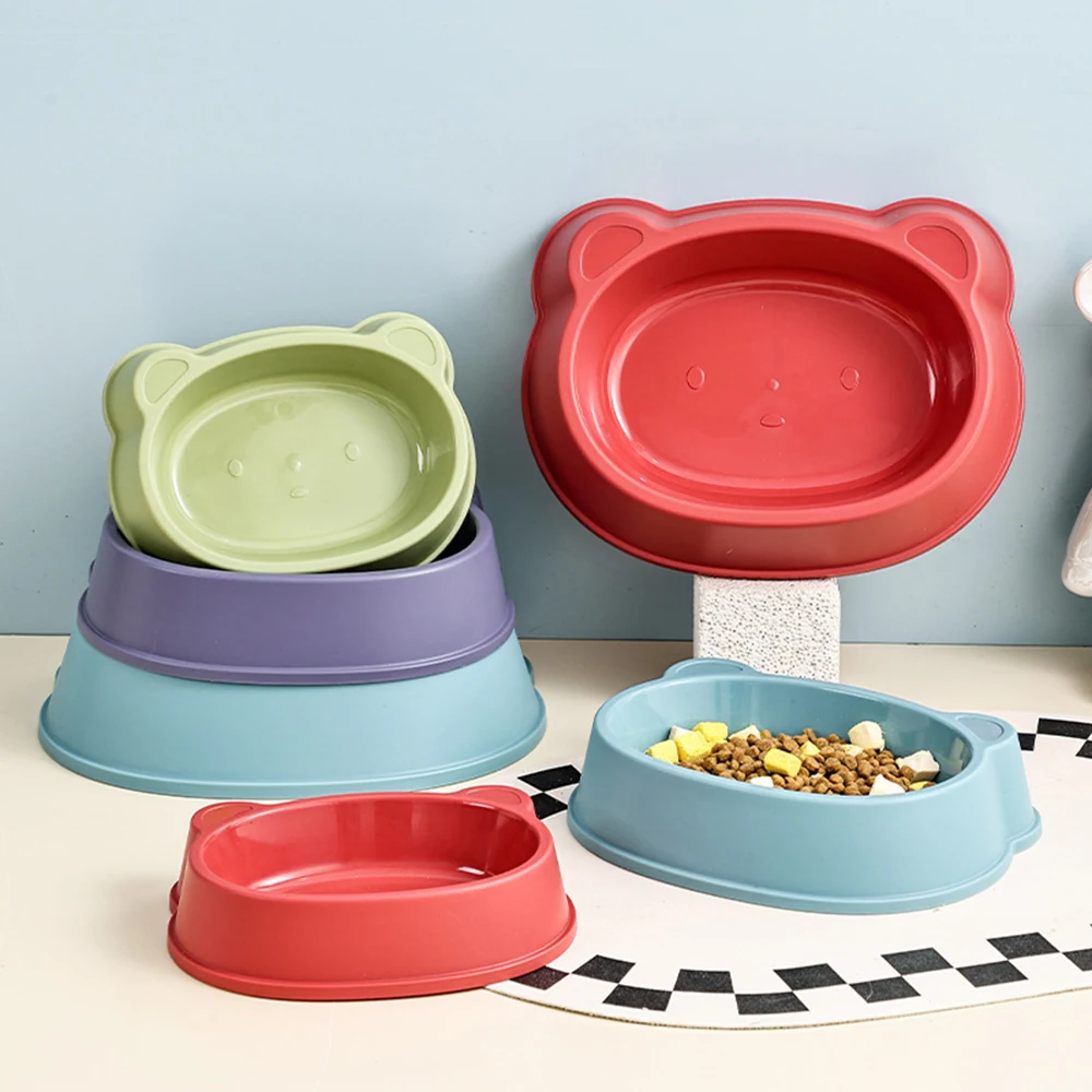A set of colorful bear-shaped plastic pet bowls arranged on a table with food.