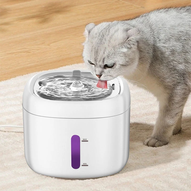 A white pet water fountain with a purple indicator window being used by a grey cat.