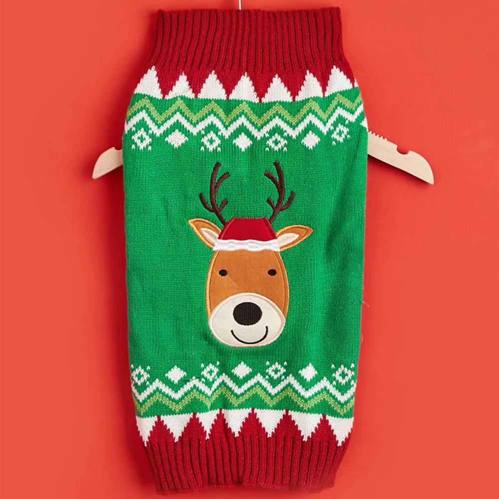 Green knitted pet sweater with a reindeer face design and red cuffs hanging on a hanger.