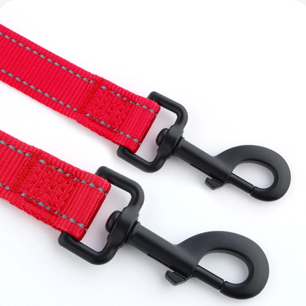 Two red nylon webbing straps with black metal swivel snap hooks and reflective stitching