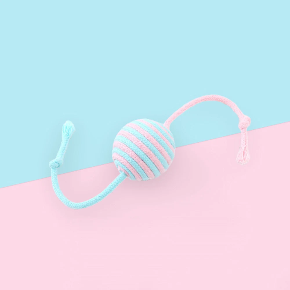 A pink and blue striped yarn ball with two attached strings on a two-tone pastel background.