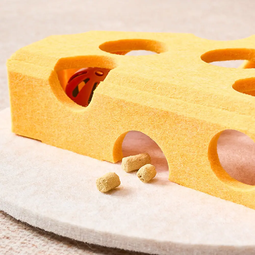 A yellow foam pet toy with holes containing a ladybug and scattered pellets.