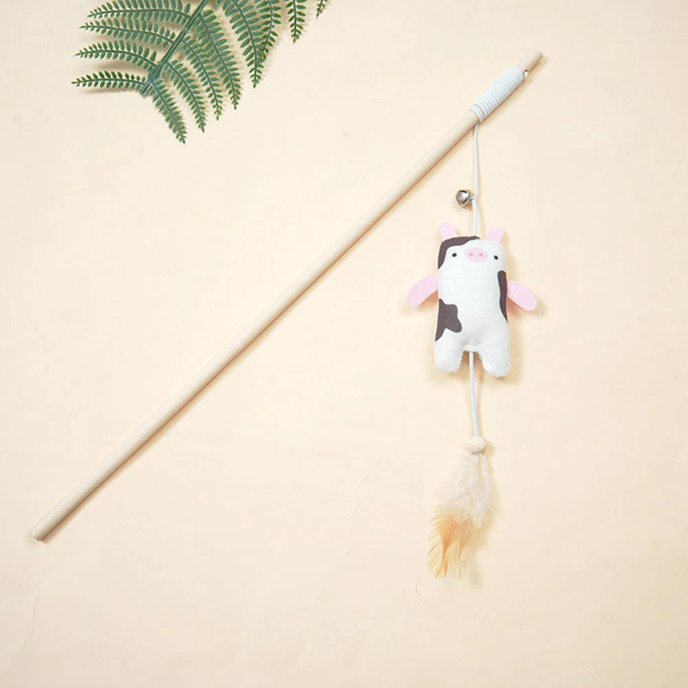 Cow-shaped plush cat teaser wand with feather attachment on beige background