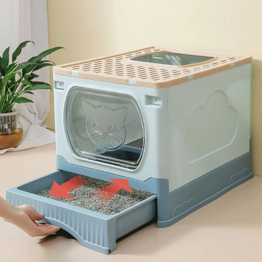 A hand pulls a tray of cat litter from a beige and blue enclosed litter box with a clear door.