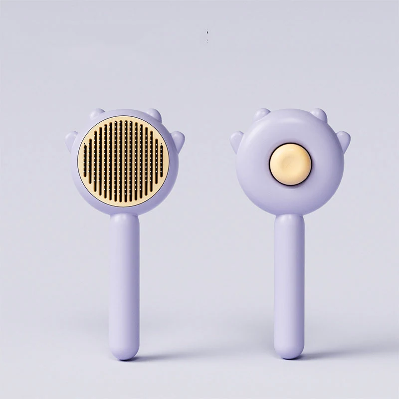Front and back view of a purple pet grooming brush with gold bristles and bear ear design.