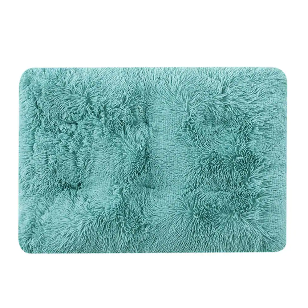 A rectangular, fluffy teal bath mat with rounded corners on a white background.