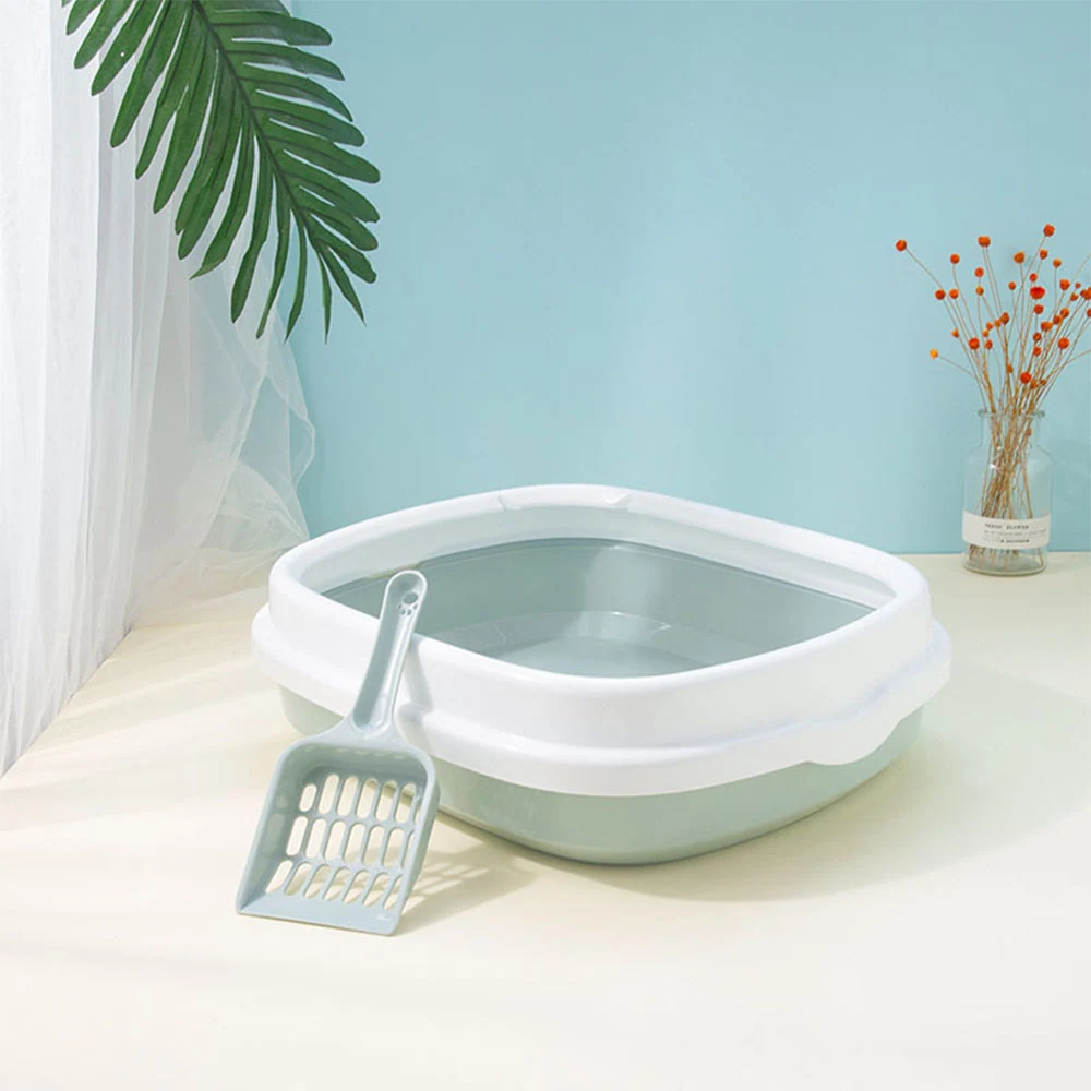 Light green and white plastic cat litter box with a matching scoop sitting on a table.