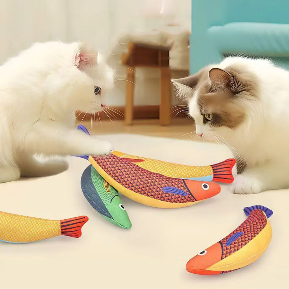 Two cats interacting with colorful plush fish toys on a floor