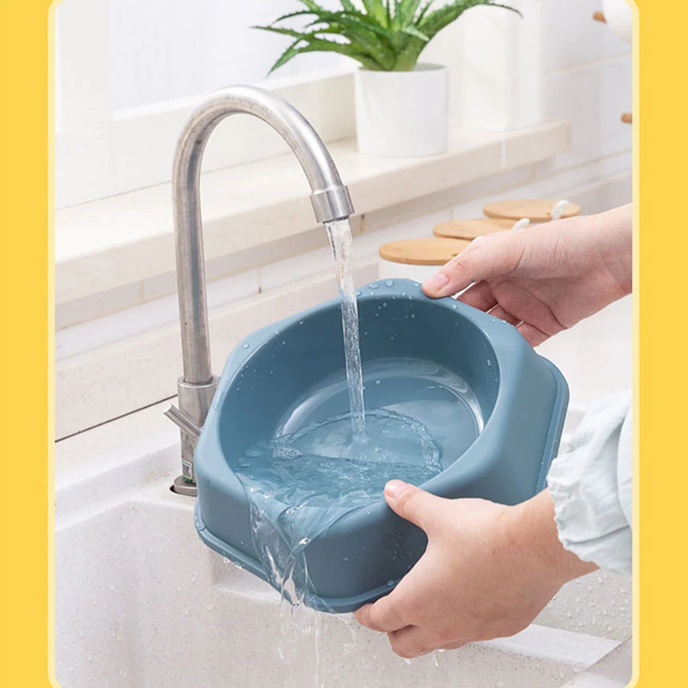 Hands rinsing a blue plastic basin under a running faucet in a kitchen sink.