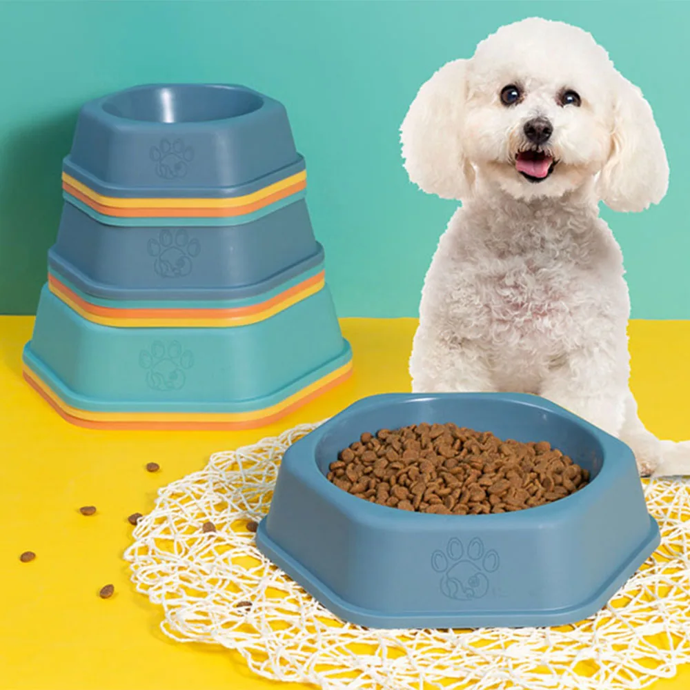 Stack of blue dog bowls with orange rims and a single bowl filled with kibble next to a white dog.