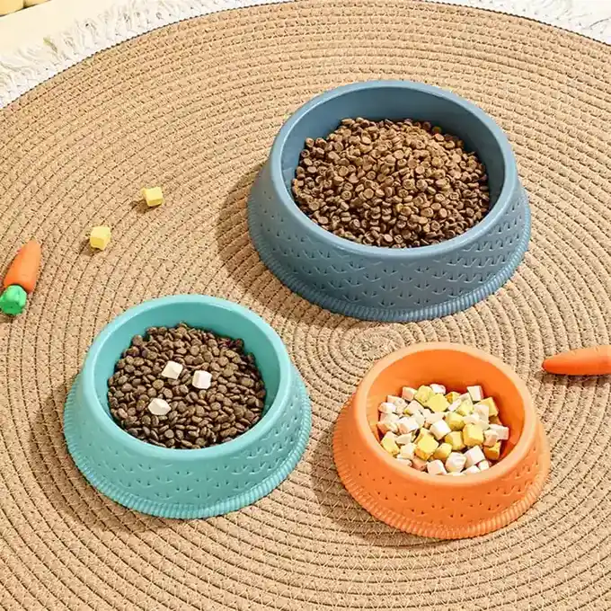 Three colorful pet food bowls filled with kibble arranged on a round woven rug.