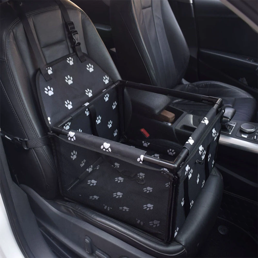 Black pet carrier with white paw prints installed on a car seat