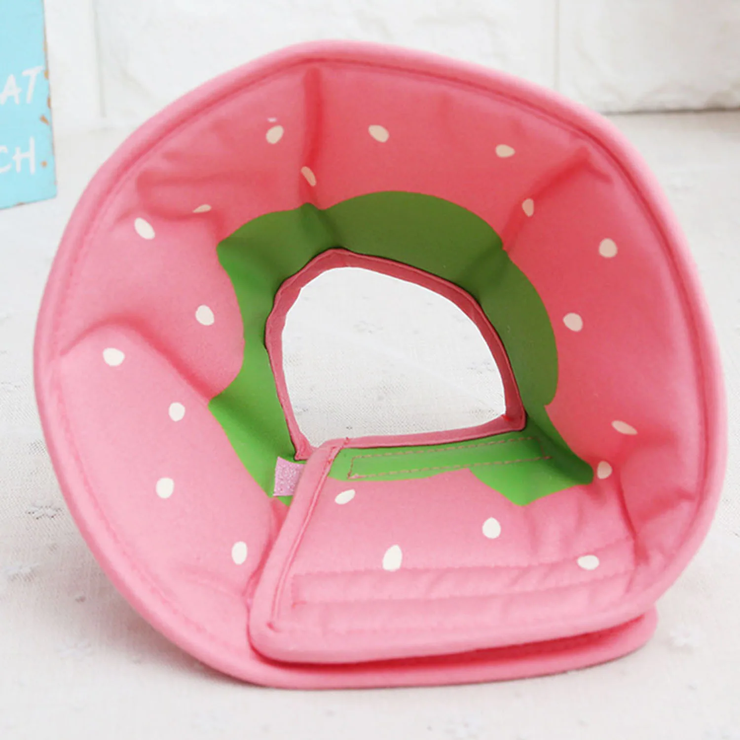 Pink watermelon shaped neck pillow with green trim and white seeds