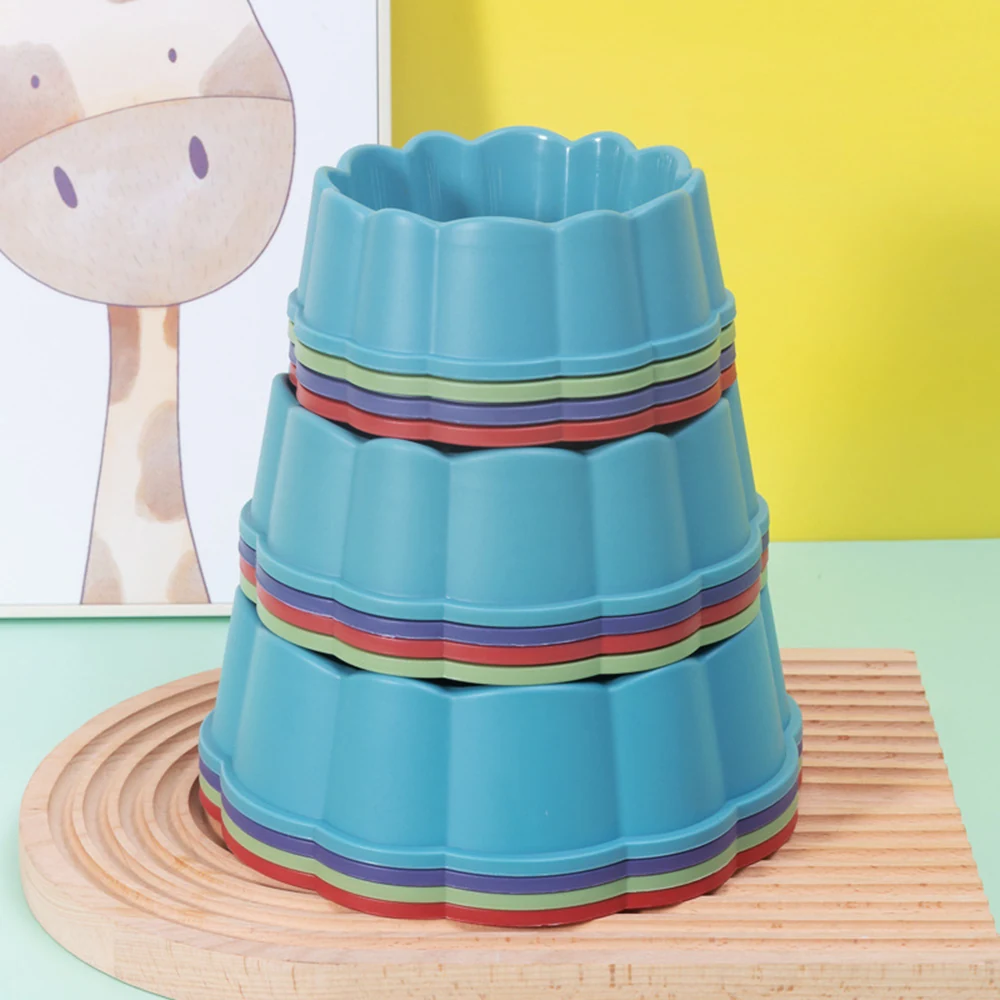 Stack of blue flower-shaped silicone molds with multicolored rims resting on a wooden coaster