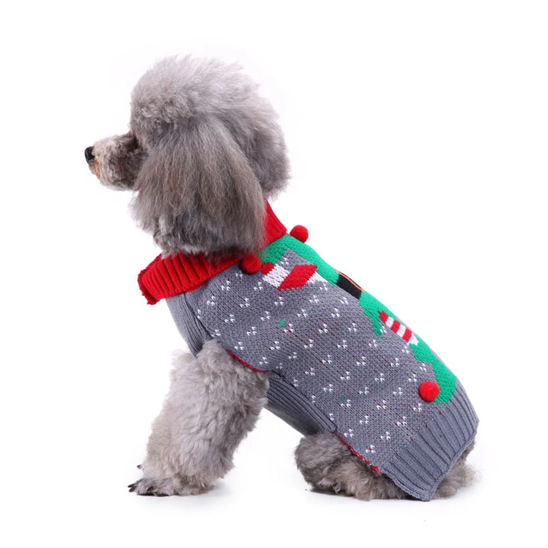 A grey poodle wearing a knitted grey sweater with a Christmas tree design and a red collar.