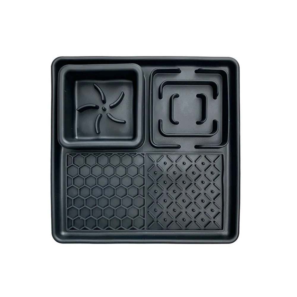 Black plastic tray with four textured compartments on a white background