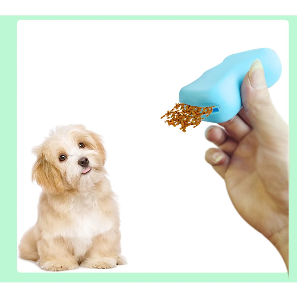 A hand holds a blue treat dispenser, offering a treat to a small, fluffy dog.