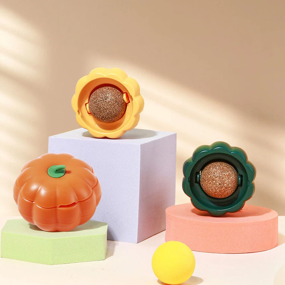 Three plastic pumpkin-shaped containers, two open to show a textured ball, on pastel pedestals.