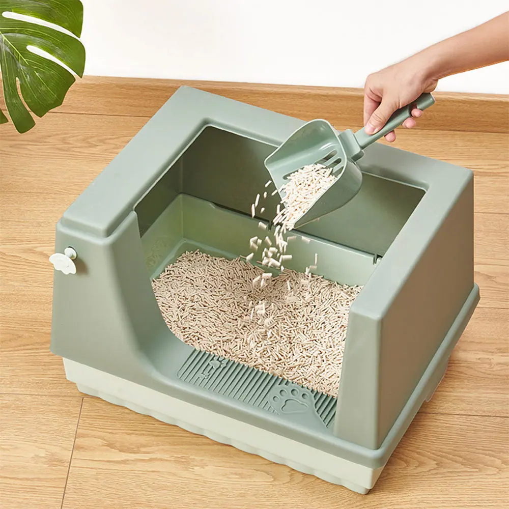A person uses a scoop to pour litter into a large, grey, top-entry cat litter box.