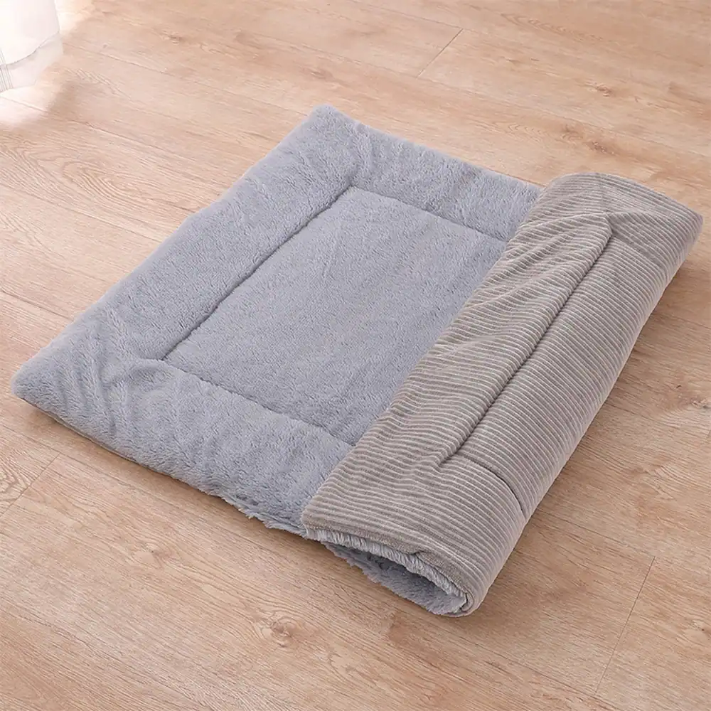 Grey plush pet mat partially rolled up on a wooden floor