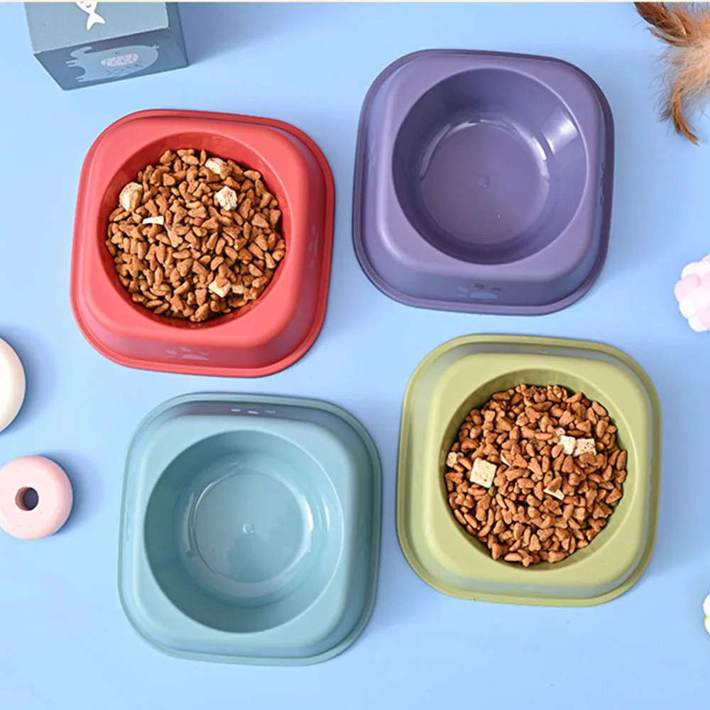 Four square pet bowls in red, purple, green, and blue, with two filled with dry food.