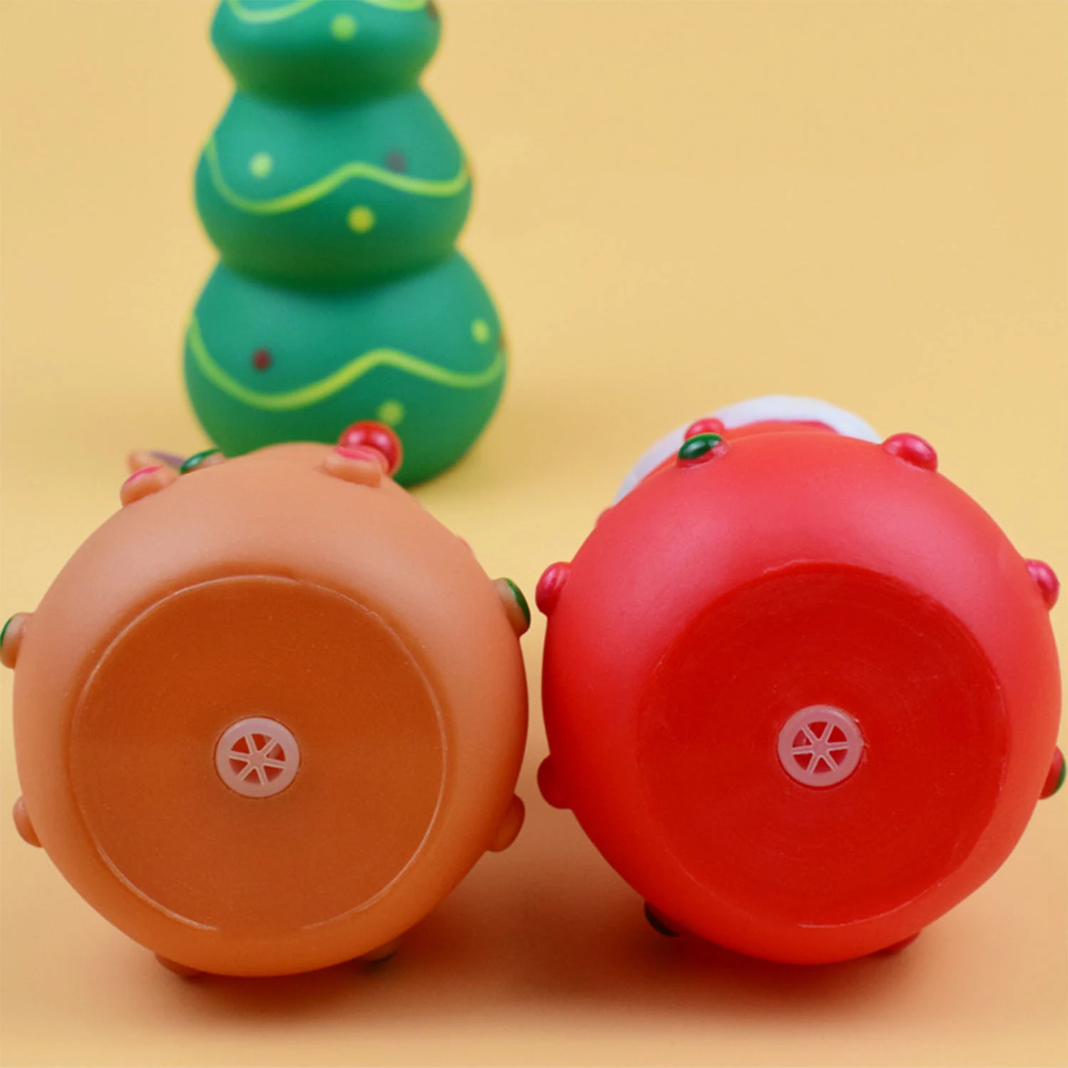 Close up of the bottom of two round plastic Christmas toys, one orange and one red, showing the winding mechanism.