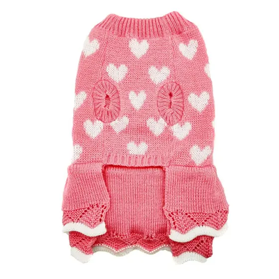 Pink knitted sweater with white hearts, textured circular accents, and a ruffled hem.