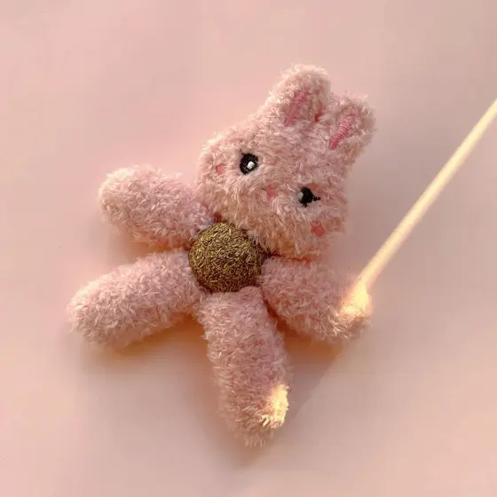 Pink fluffy knitted bunny brooch with a gold button center on a stick