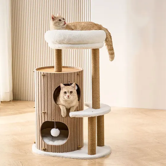 Beige cat tree with a top perch and two cylindrical cubbies, occupied by two cream cats.