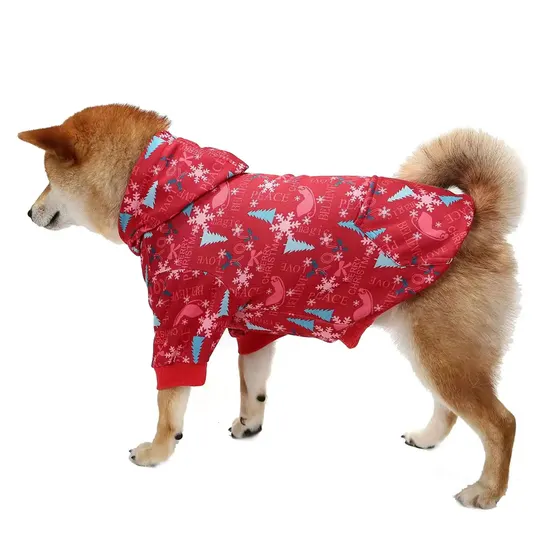 Side profile of a Shiba Inu dog wearing a red hooded winter coat with a snowflake and tree pattern against a white background.